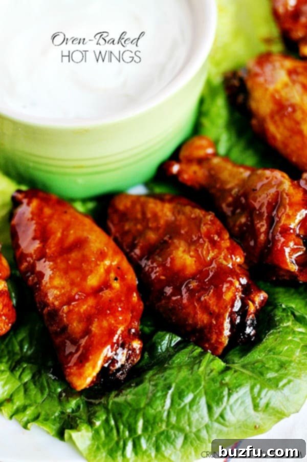 Healthier Oven Baked Hot Wings: Crispy chicken wings tossed in a sweet and spicy sauce. Close up shot of crispy oven-baked hot wings on a fresh lettuce leaf, ready to serve.