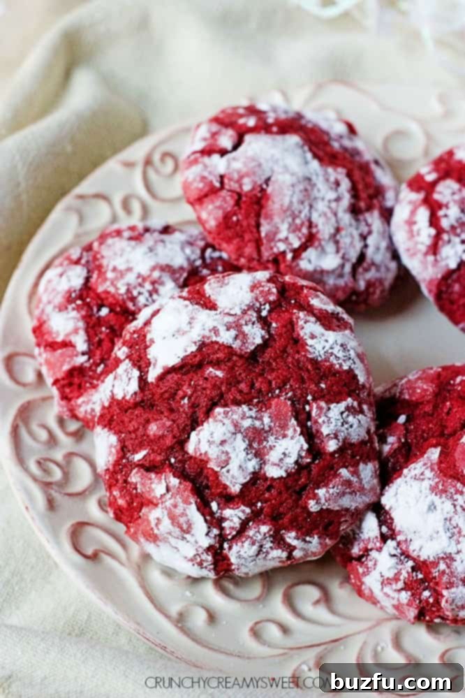 Close-up of vibrant red velvet crinkle cookies with white powdered sugar.