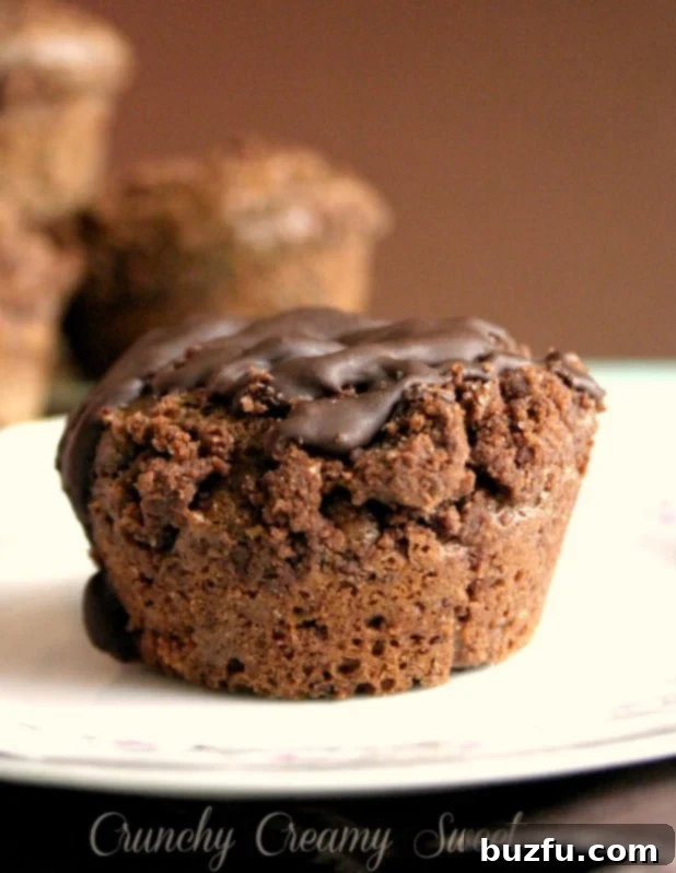 Moist Cocoa Muffin with Chocolate Drizzle A close-up view of a perfectly baked cocoa muffin, topped with a rich streusel and drizzled with melted chocolate, resting on a wire rack.