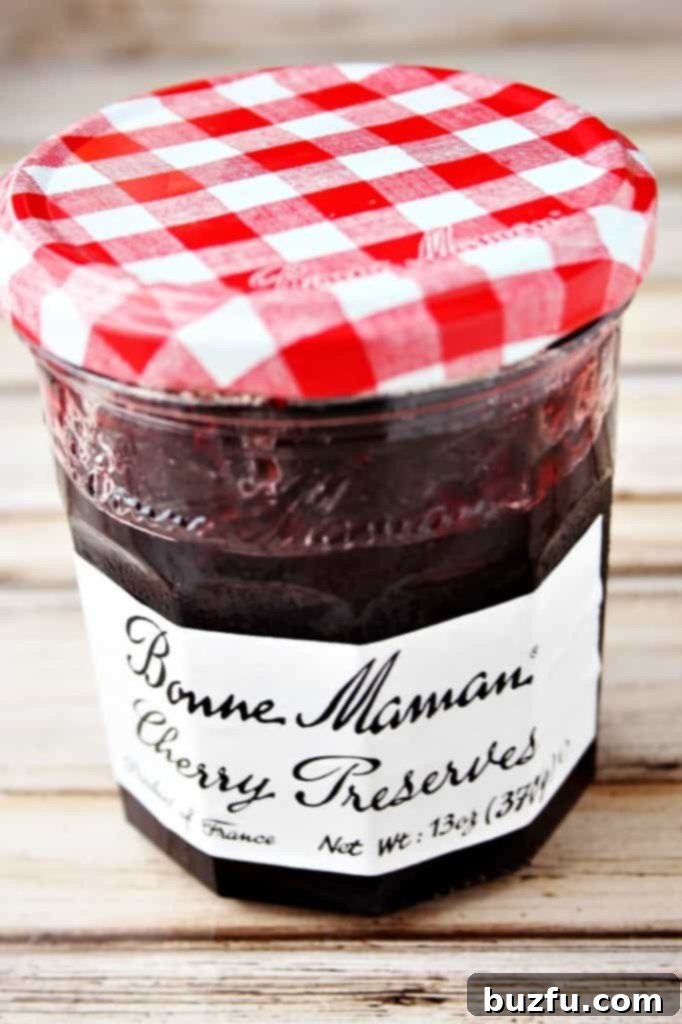 A jar of Bonne Maman Cherry Preserves, featuring its signature red and white gingham lid, highlighting its natural ingredients.