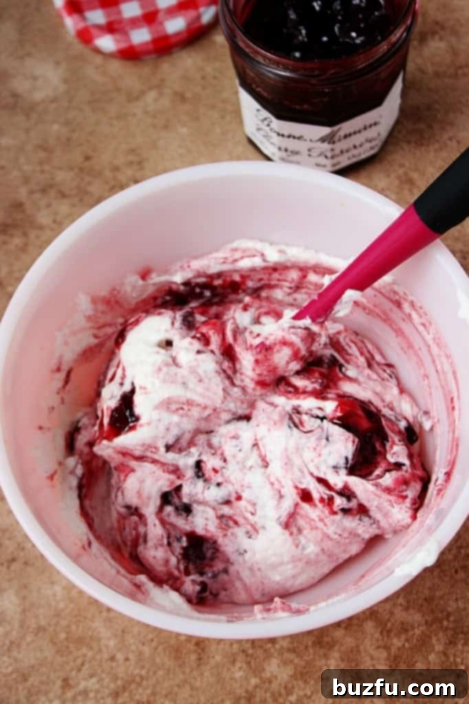 Close-up of a bowl filled with homemade Cherry Preserves Cream Frosting, showcasing its light, fluffy texture and hints of cherry.