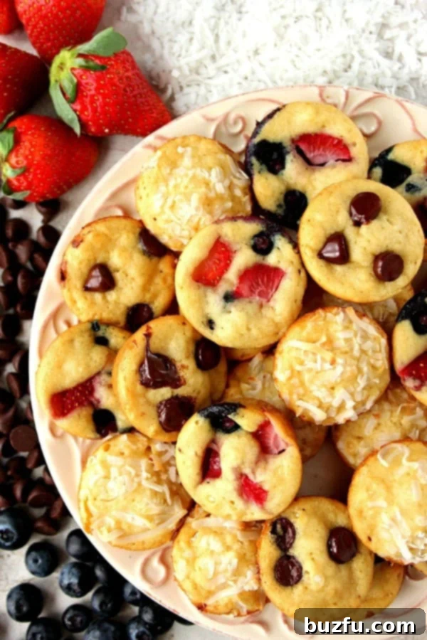 A plate of golden brown Mini Pancake Muffins topped with fresh berries and chocolate chips.
