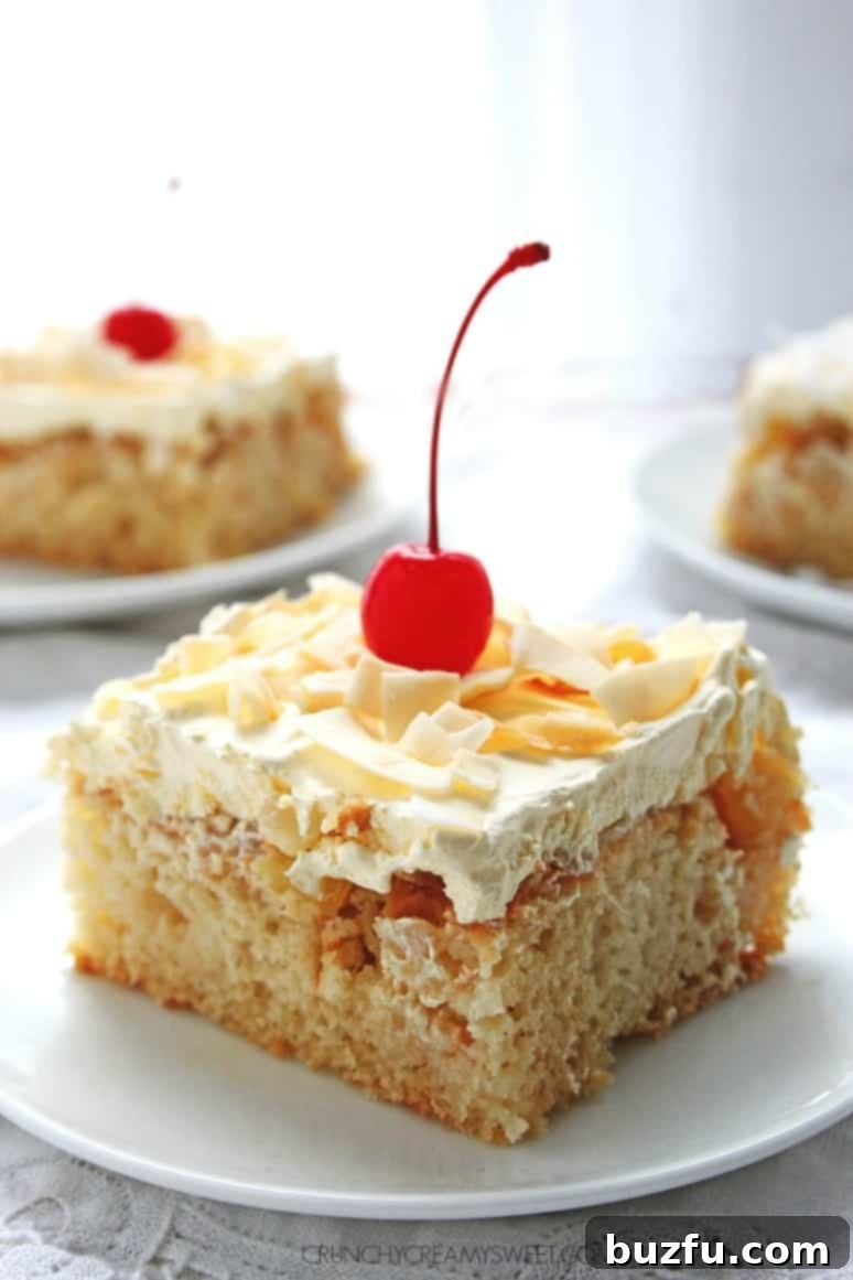 An overhead shot of the full Pina Colada Cake, topped generously with creamy white frosting, coconut flakes, and bright red maraschino cherries, ready to be sliced.