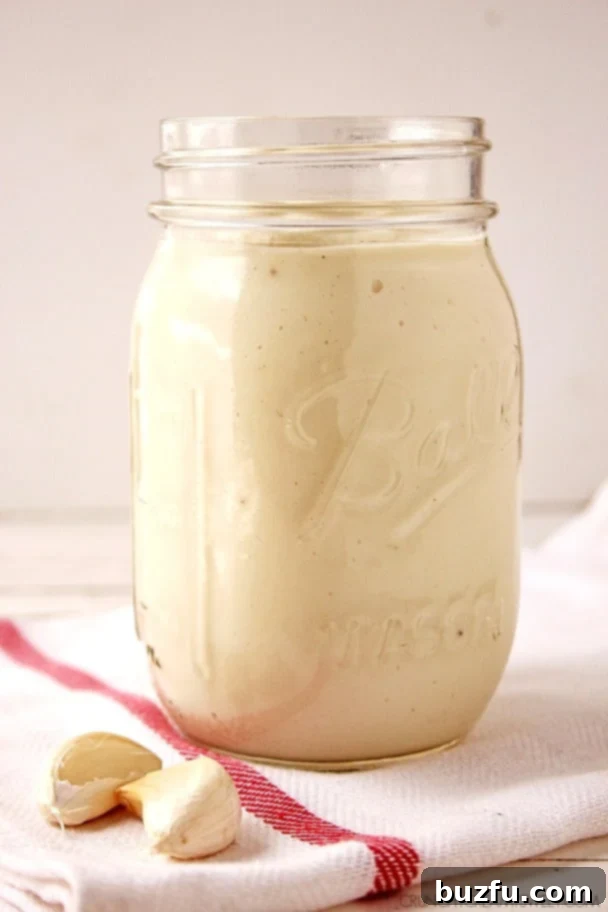 Side shot of creamy cauliflower Alfredo sauce in a jar, without lid, ready for storage or serving.