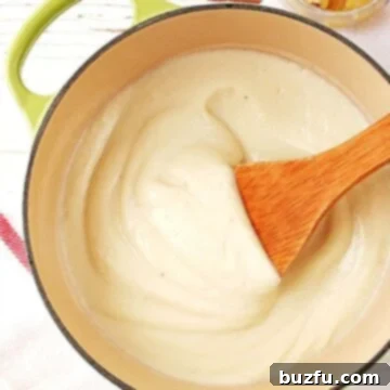 Cauliflower Alfredo Sauce in a saucepan, garnished with fresh parsley.
