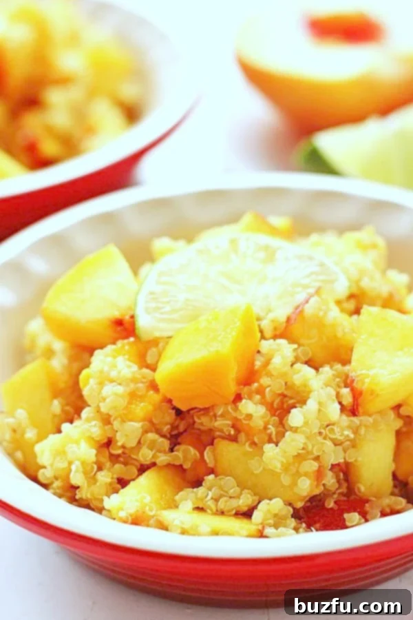 A vibrant bowl of Mango Peach Quinoa Salad, featuring diced mangoes, peaches, and fluffy quinoa, glistening with honey lime dressing.