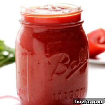 Homemade Pizza Sauce in a glass jar on a white kitchen towel.