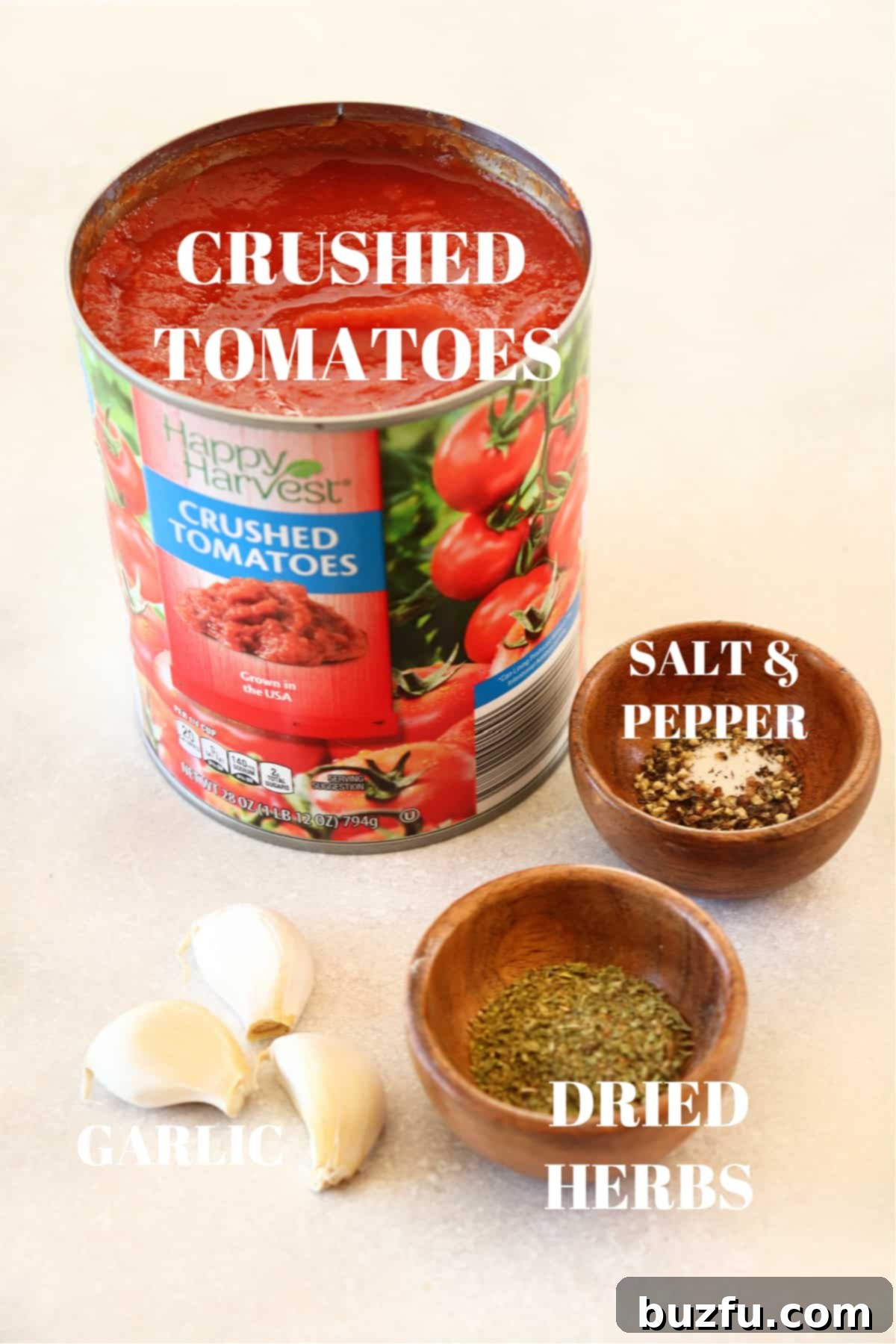 A selection of fresh ingredients including a can of high-quality crushed tomatoes, whole peeled garlic cloves, and small wooden bowls filled with mixed dried herbs and spices, all artfully arranged on a rustic grey board, highlighting their natural appeal.