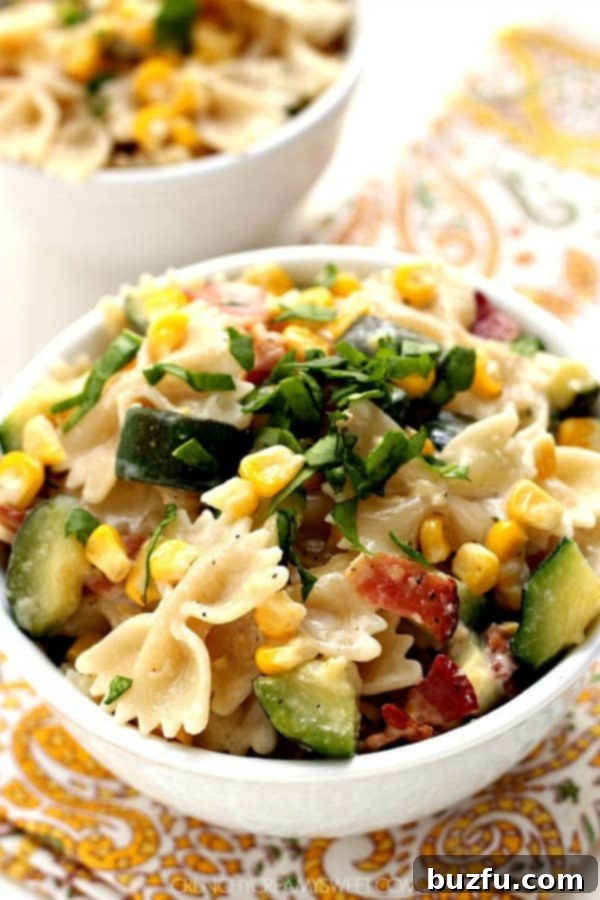 Creamy Corn and Zucchini Pasta with Crispy Bacon in a white bowl, garnished with fresh herbs.