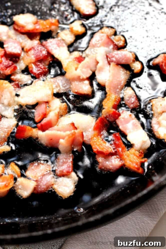 Crispy bacon sizzling in a cast iron skillet, ready for vegetables to be added.