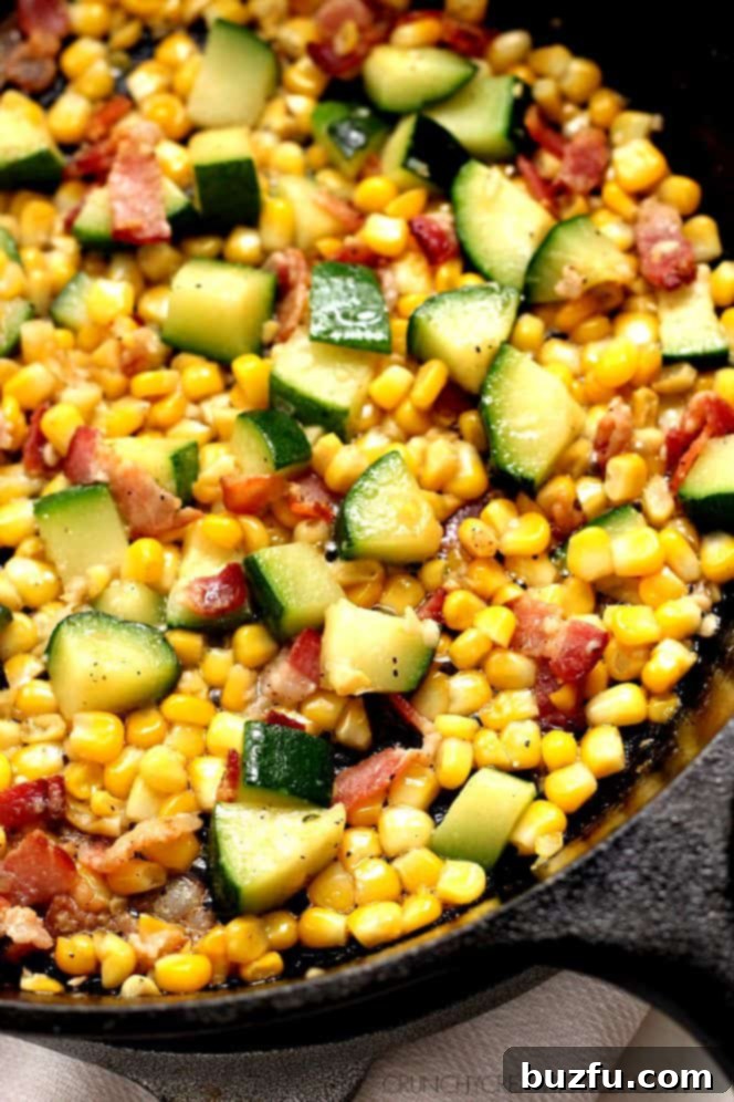 Freshly chopped zucchini and sweet corn being sautéed in a skillet with bacon fat.