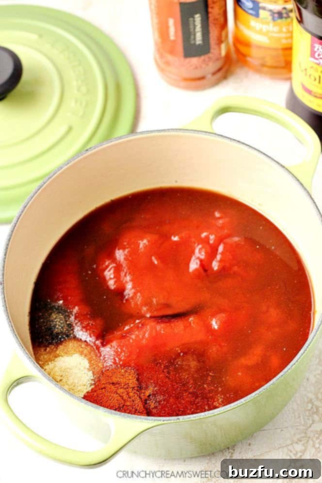 Side shot of BBQ sauce ingredients bubbling in a saucepan on the stovetop.