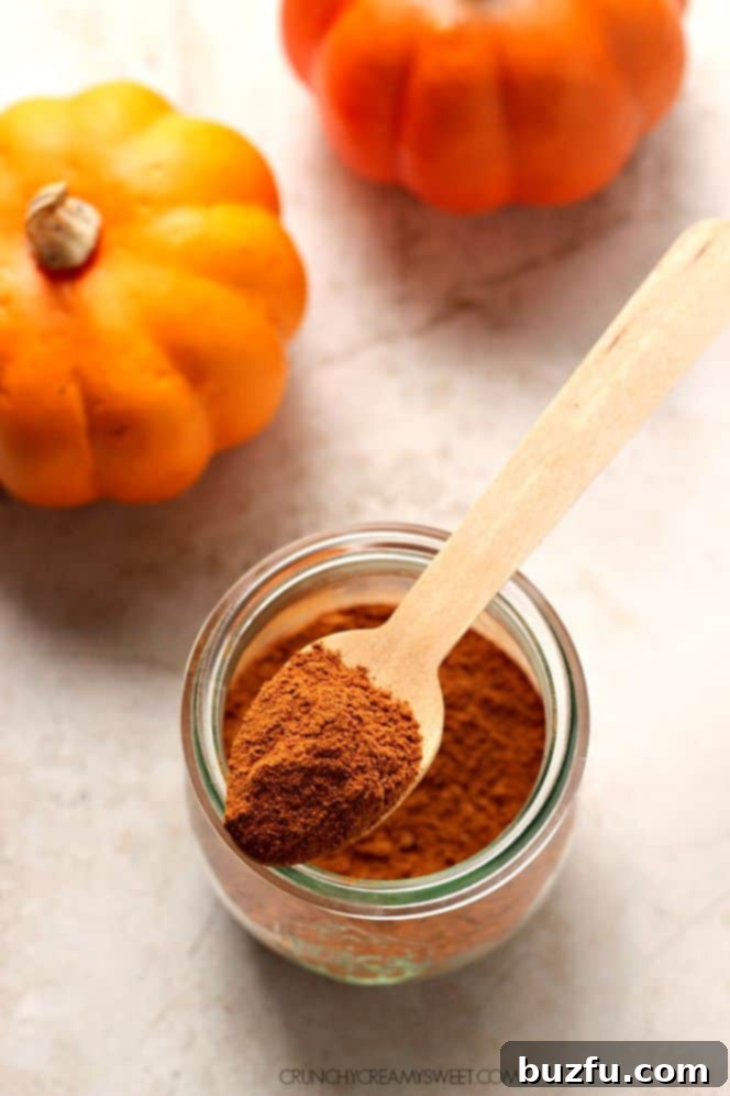 Homemade pumpkin spice mix in a small bowl with whole spices around it.