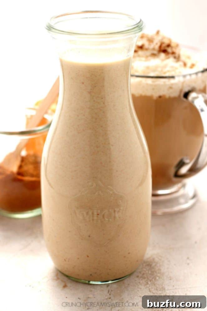 Homemade pumpkin spice coffee creamer in a small glass bottle with a coffee mug.