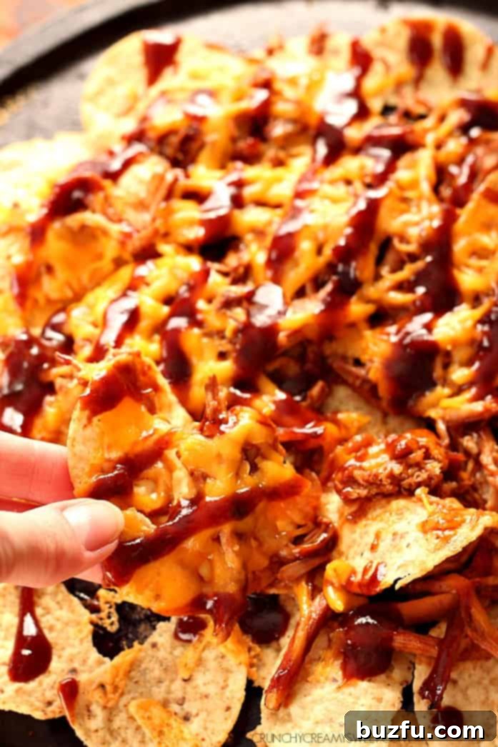 Bite being taken off Pulled Pork Nachos with cheese.