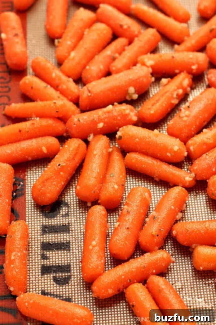 Close-up of roasted baby carrots with visible garlic bits and melted Parmesan cheese.