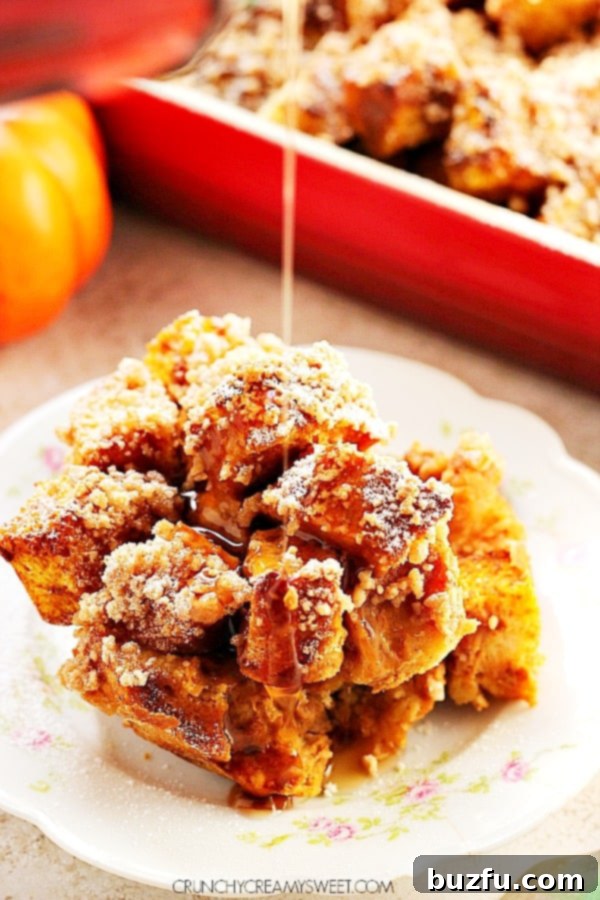 A perfectly portioned serving of Pumpkin French Toast Casserole, garnished with powdered sugar, on a white plate. The golden crust and soft interior are visible, inviting a delicious taste.