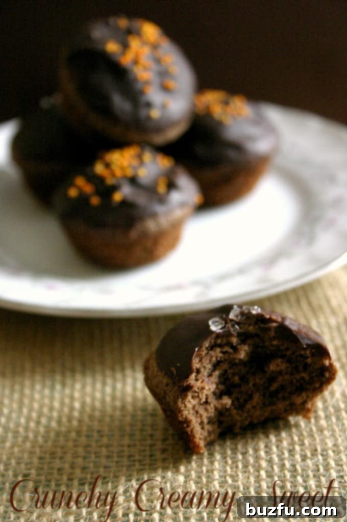 Close-up of a brownie bite with one small bite missing, showing the moist, fudgy interior and glossy chocolate glaze, suggesting its deliciousness.