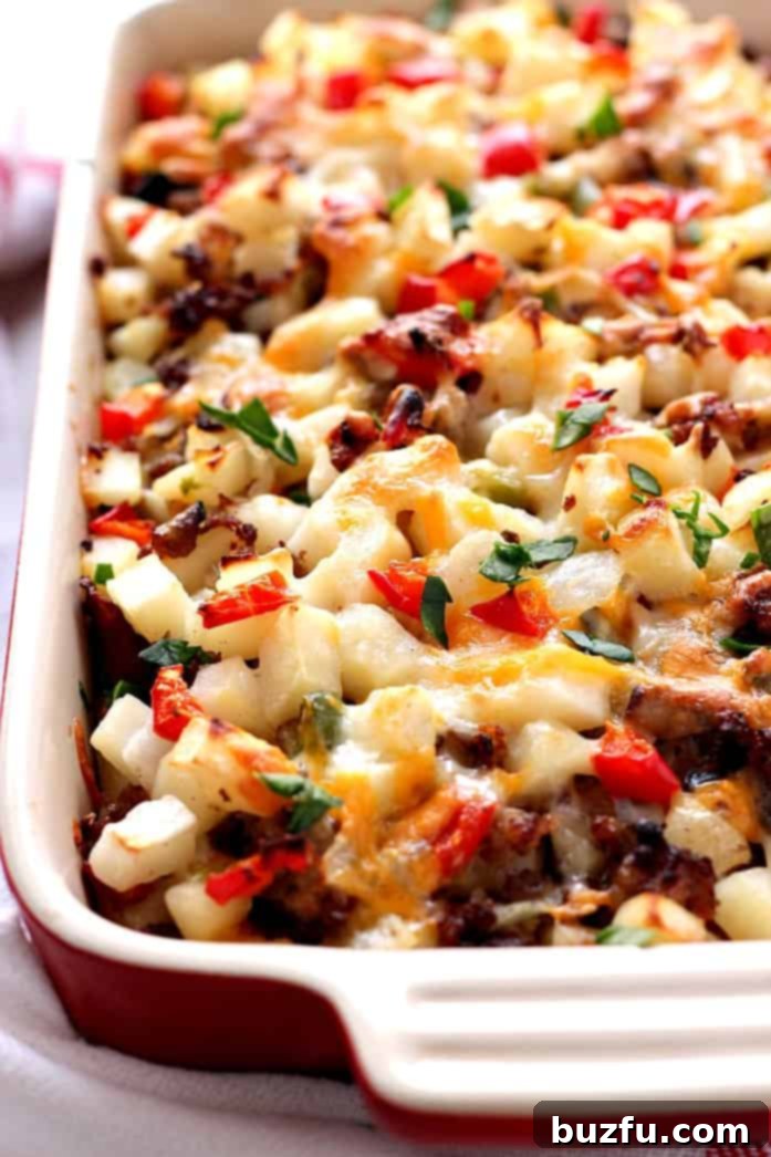 Make Easy Breakfast Casserole with hash browns and sausage. A close-up shot of a baked Breakfast Casserole with melted cheese and visible ingredients like sausage, peppers, and hash browns, in a rectangular baking dish.