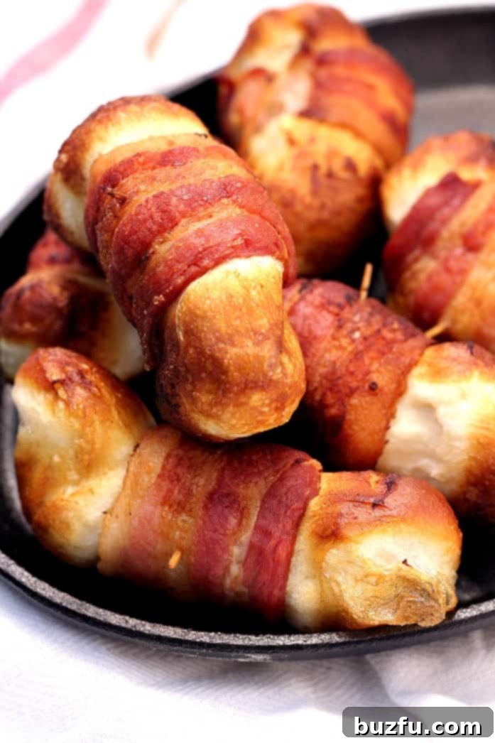 Bacon Wrapped Cheese Bombs - the appetizer that will make the party! Cheese filled biscuit bombs wrapped in bacon and fried. Do it! A close-up of a stack of freshly fried bacon wrapped cheese bombs, showing the crispy bacon and golden biscuit exterior.
