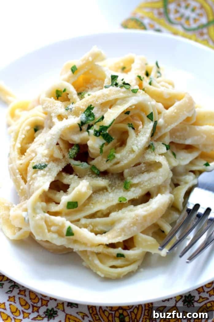Serve Your Skinny Fettuccine Alfredo Warm with Fresh Garnishes A close-up of Skinny Fettuccine Alfredo served on a white plate with fresh parsley.