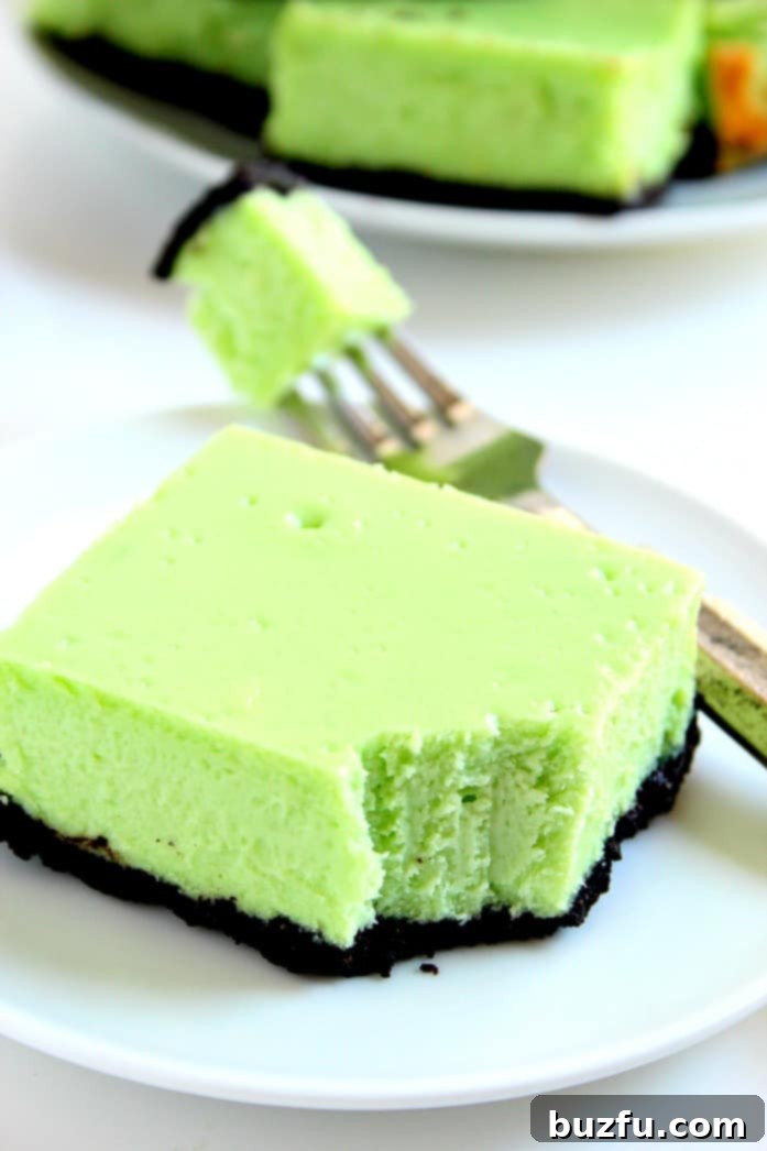 A close-up of a single Mint Cheesecake Bar, showcasing its creamy texture and chocolate cookie crust.