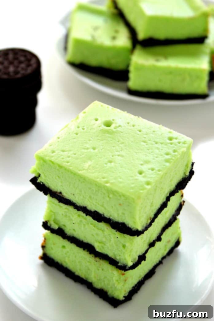Close-up of a beautifully sliced Mint Cheesecake Bar, showing the distinct layers of mint cheesecake and Oreo crust.