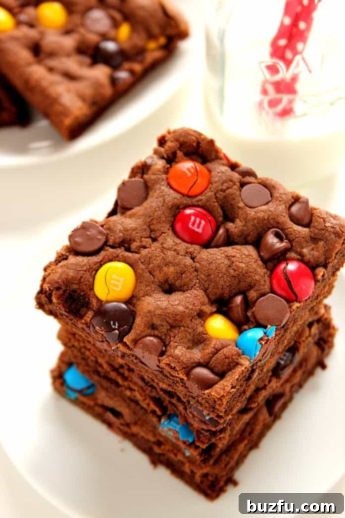 Stack of rich Chocolate M&M Cookie Bars on a white plate, ready to be enjoyed.