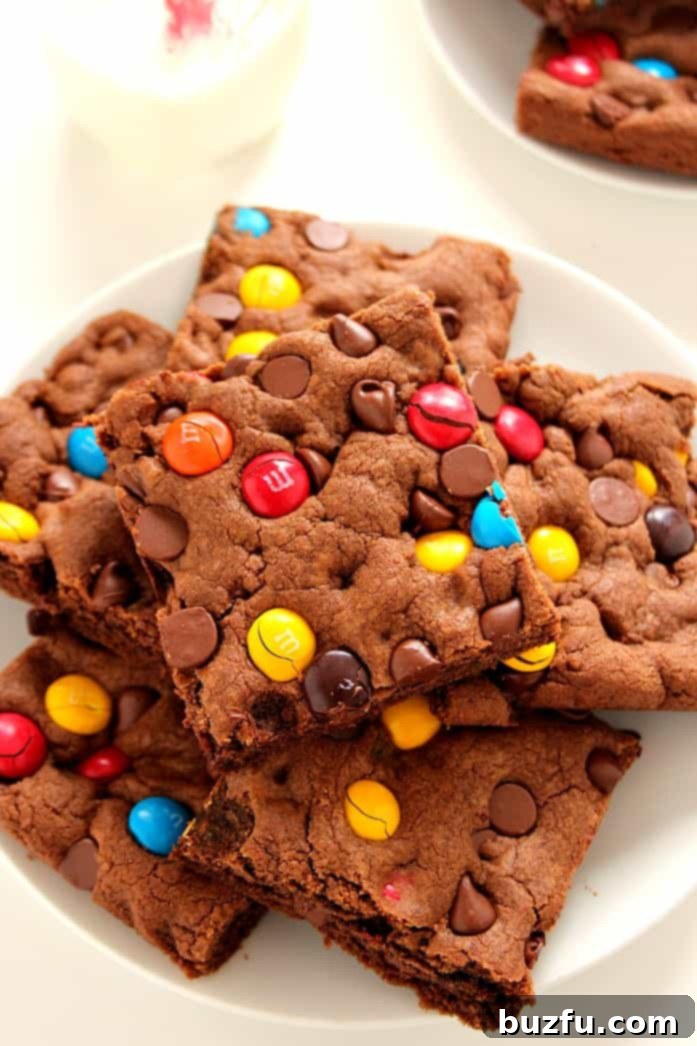 Close-up of a perfectly cut chocolate cookie bar with colorful M&M's and chocolate chips.
