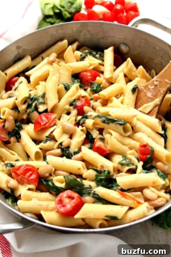 Close-up of pasta and vibrant vegetables simmering in a skillet, showcasing the rich sauce.