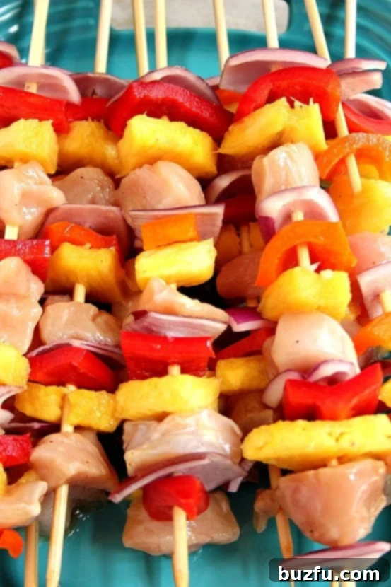Pineapple chicken kabobs before grilling. Arranged neatly on a baking sheet, showcasing fresh chicken, pineapple, and colorful vegetables, ready to be cooked.