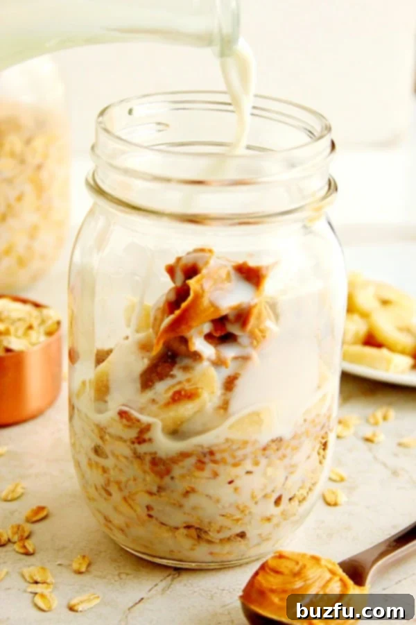 Side shot of oats with peanut butter in jar, with milk being poured in.