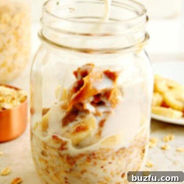 Oats and peanut butter in glass jar, milk being poured in.