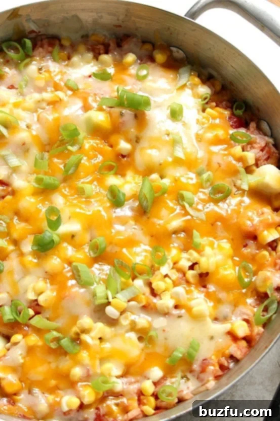 Close-up of Cheesy Salsa Rice with Zucchini and Corn in a skillet, showcasing the melted cheese and colorful vegetables.
