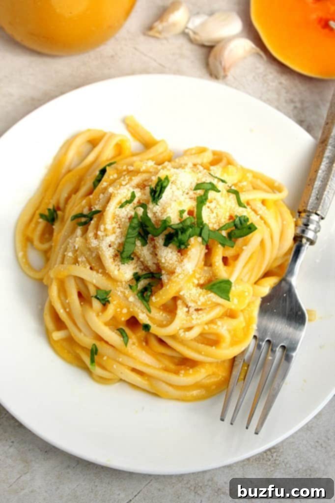 Overhead view of a white plate filled with pasta coated in creamy Butternut Squash Alfredo Sauce.