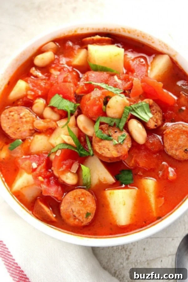 A steaming bowl of hearty Italian Sausage Soup, garnished with fresh herbs.