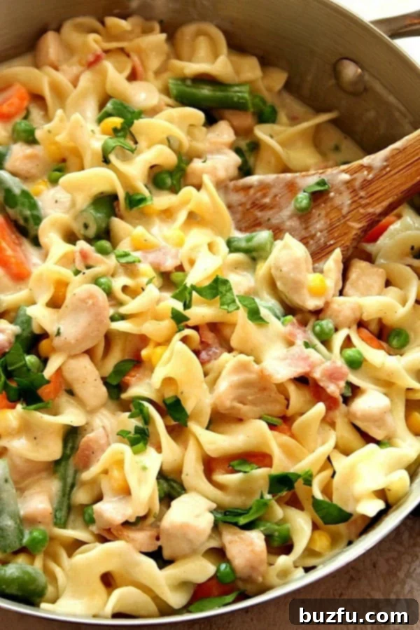 Chicken Pot Pasta in a skillet, showcasing a creamy, delicious dish with wide noodles, chicken, peas, sweet corn, carrots, and green beans.