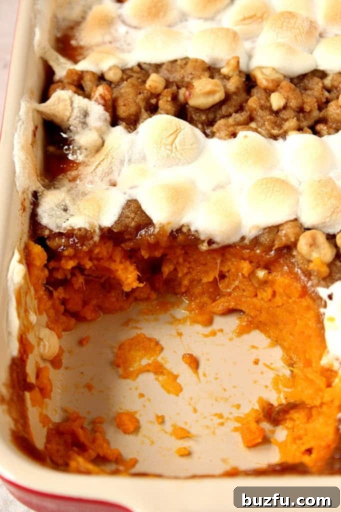 A festive sweet potato casserole, artfully topped with both golden praline and perfectly toasted mini marshmallows, embodying the spirit of Thanksgiving.