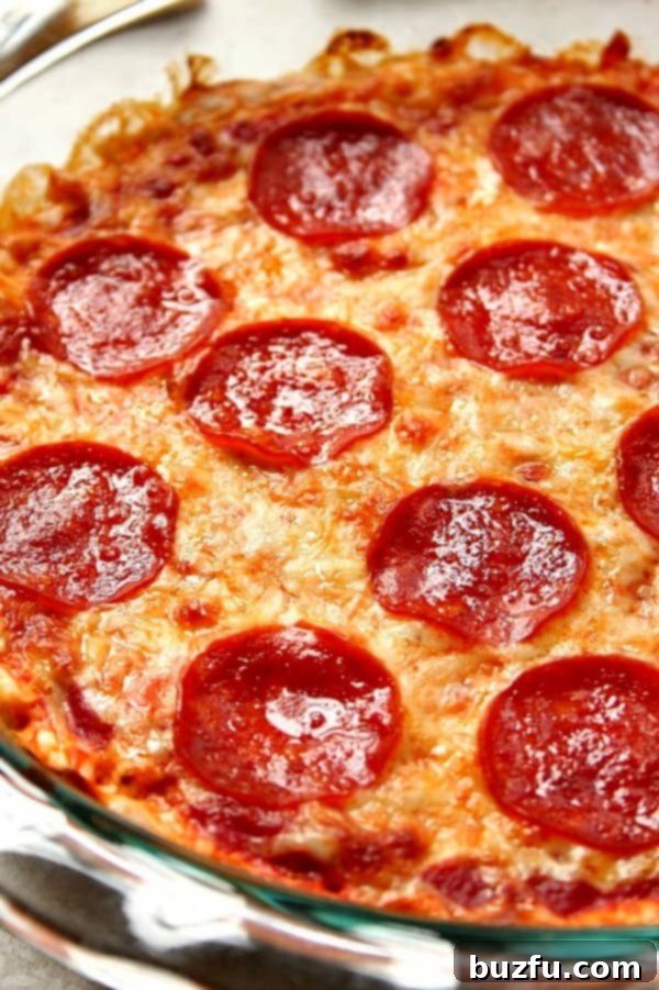 Close up shot of bubbly pepperoni pizza dip in a glass pie dish, ready to be served.