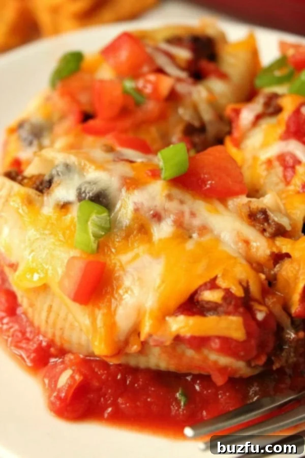 A plate of golden-brown Taco Stuffed Pasta Shells, generously topped with melted cheese and fresh garnishes.