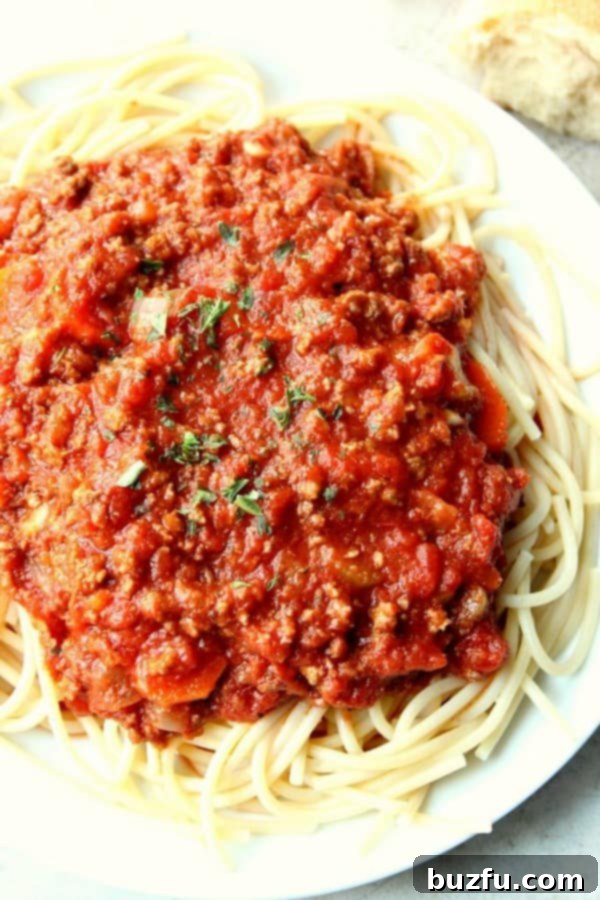 Slow Cooker Bolognese Sauce served over perfectly cooked spaghetti, garnished with fresh parsley and Parmesan cheese, ready to be enjoyed.