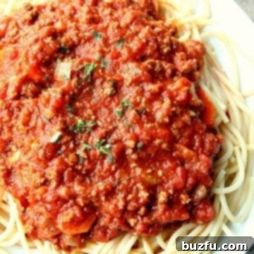 Slow Cooker Bolognese Sauce over spaghetti on plate.