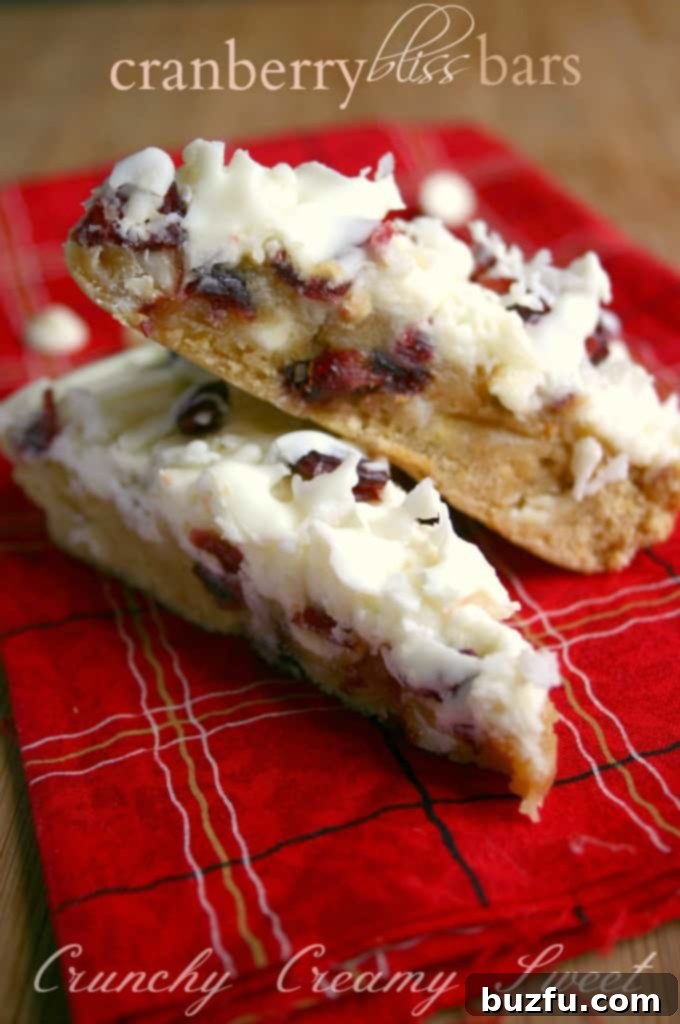 Closeup of a freshly baked Cranberry Bliss Bar with coconut, cranberries, and white chocolate drizzle
