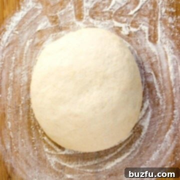 Evde Kusursuz Pizza Hamuru Yapımı 2 Pizza dough on a wooden board, ready for preparation.