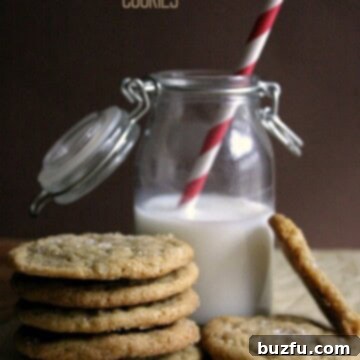 A stack of perfectly baked Brown Butter Brown Sugar Cookies on a white background, garnished with sea salt.