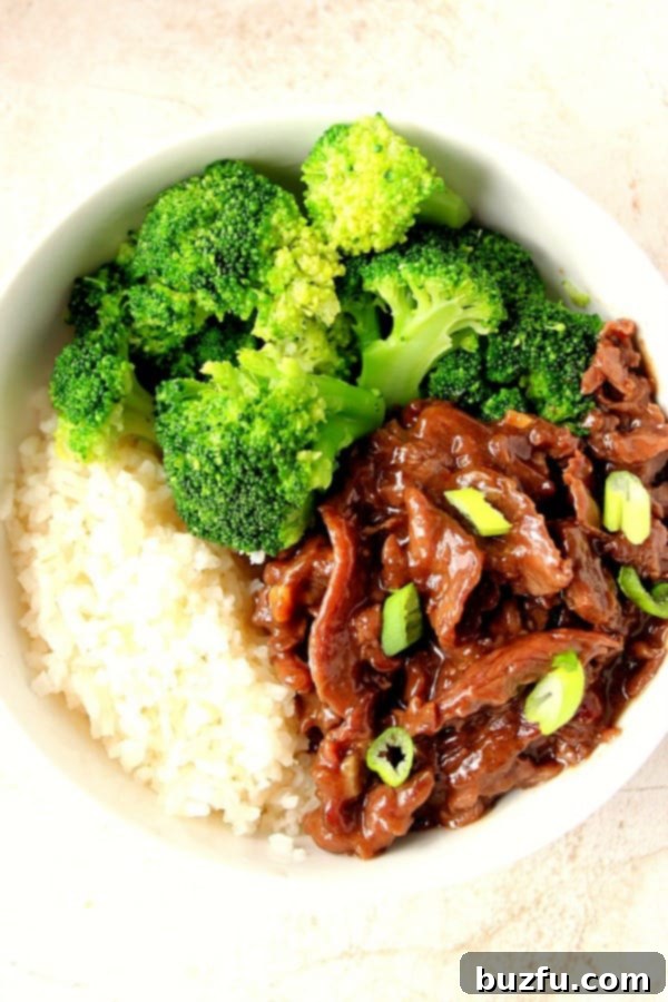 Mongolian Beef over rice with broccoli in white bowl. A delicious and quick homemade takeout copycat recipe.