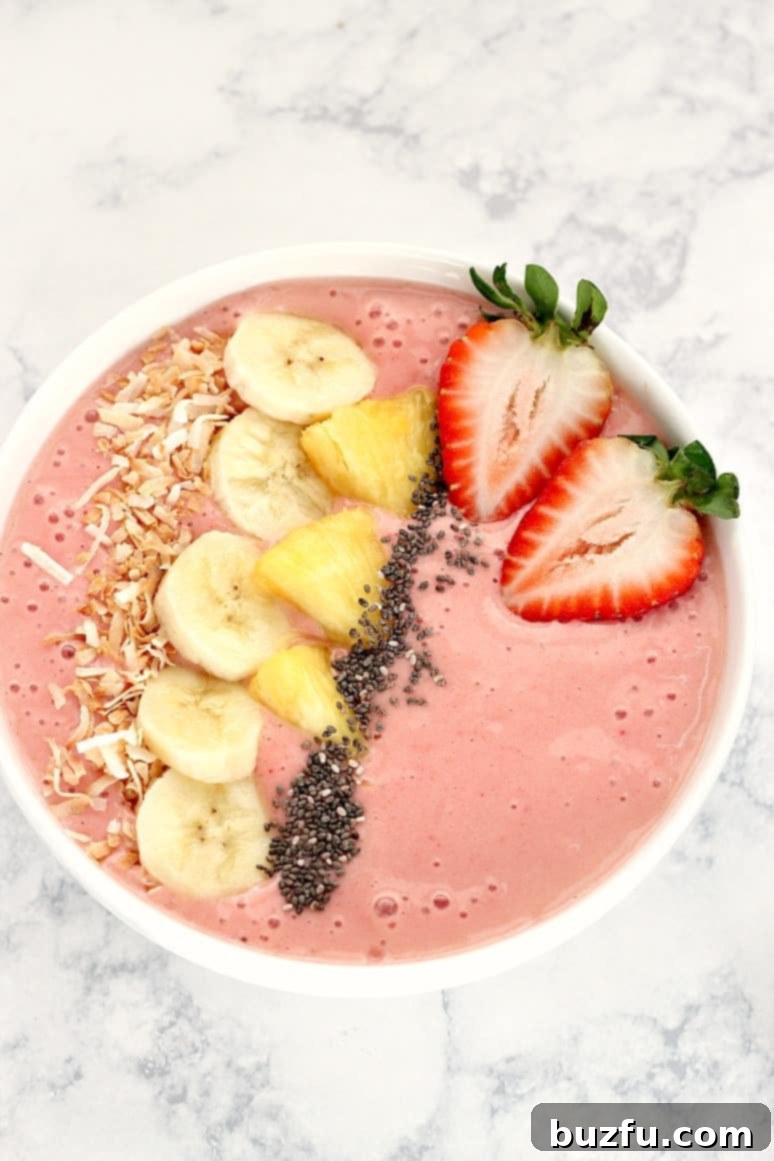 A beautifully presented strawberry pineapple smoothie bowl, garnished with fresh strawberry slices and mint leaves, ready to be enjoyed.