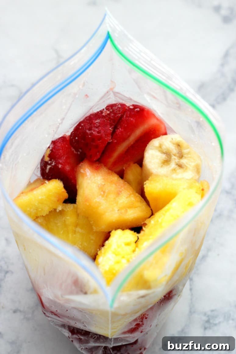 Close-up of vibrant red strawberries and golden pineapple rings, key ingredients for a delicious smoothie bowl, ready for freezing.