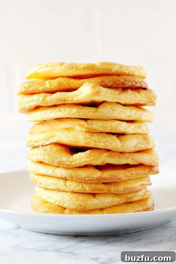 Cloud Bread Recipe - low-carb, high-protein, gluten-free substitute for bread, made with just 3 ingredients. Great for keto diet. A stack of golden-brown cloud bread slices arranged on a white plate, highlighting their light and airy texture.