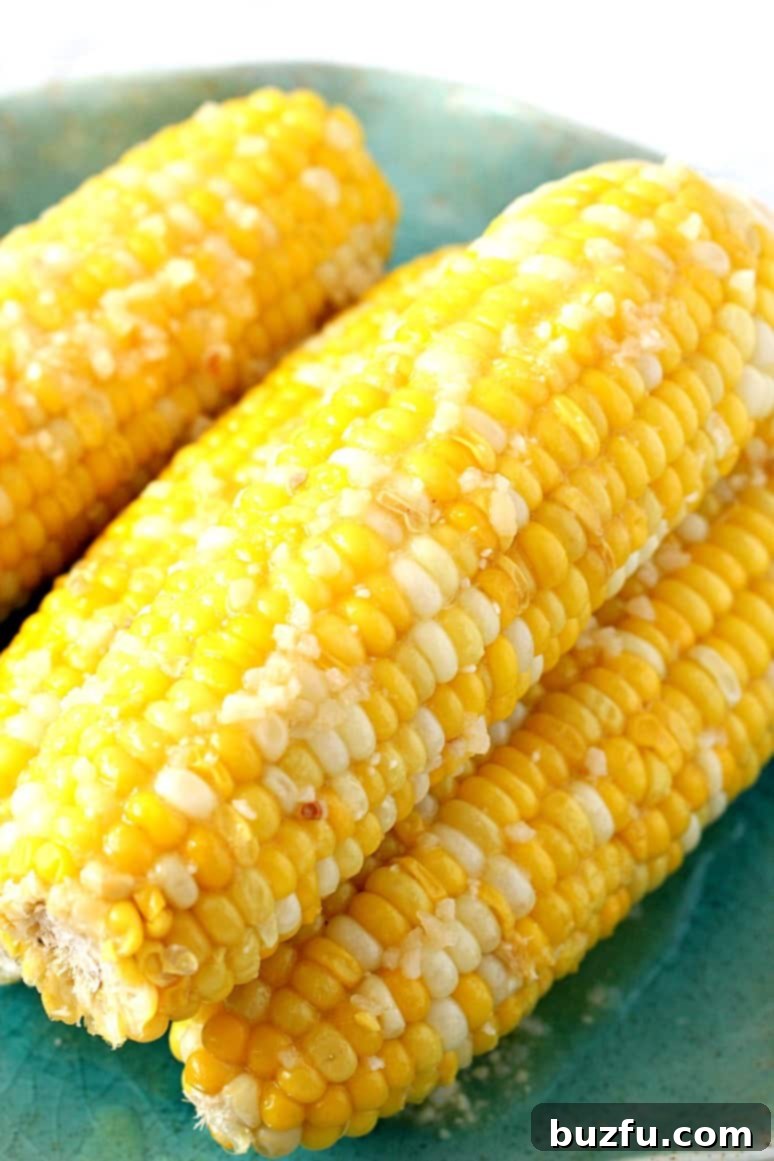 Side close up shot of corn on the cob on green plate with garlic Parmesan butter.